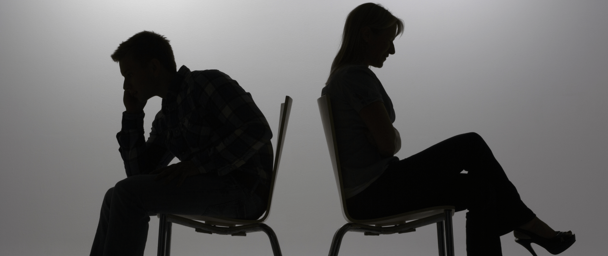 A silhouette of a man and a woman sitting opposite to each other